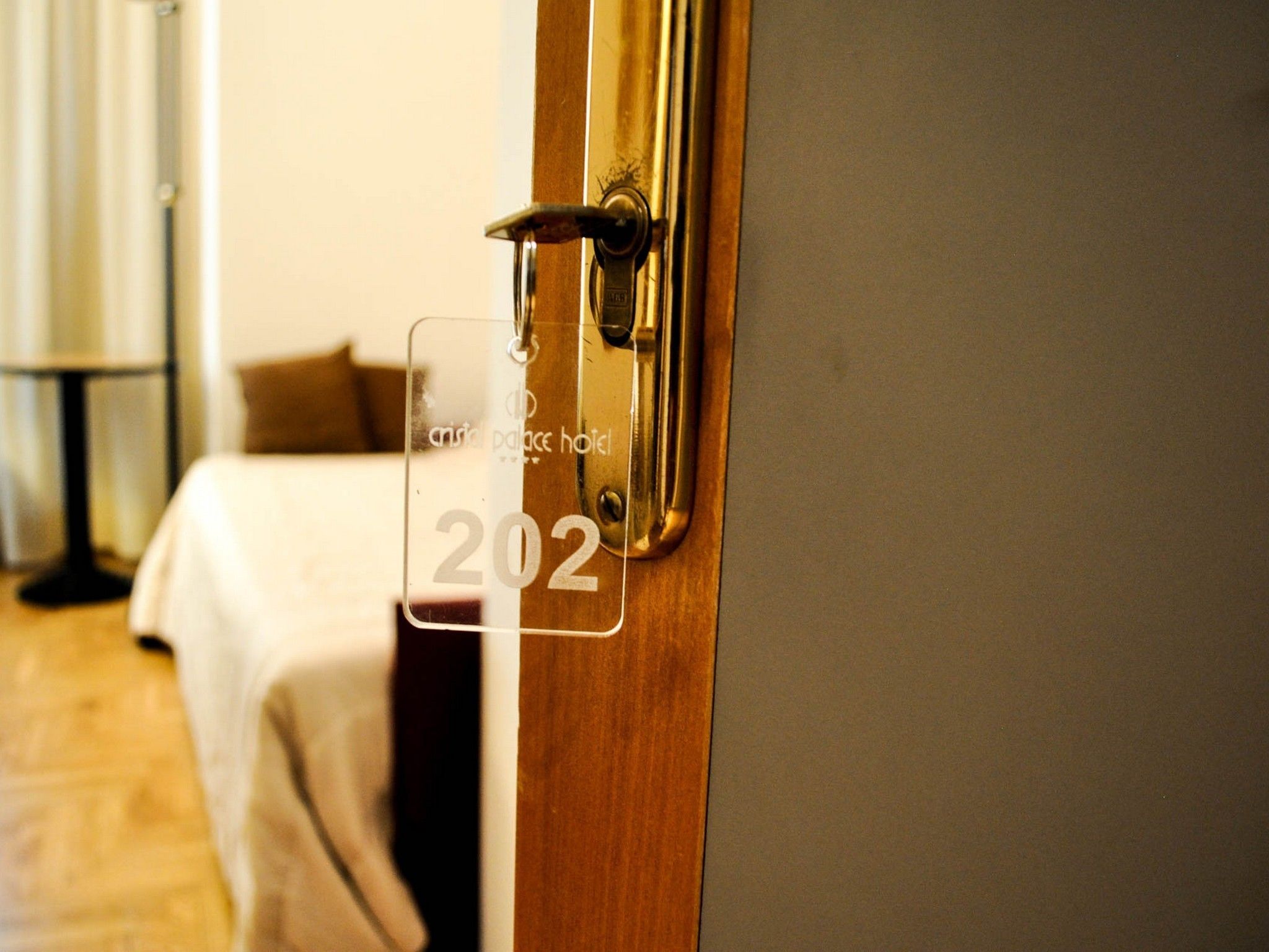 A hotel room door with a brass handle and a clear plastic sign displaying the number 202.