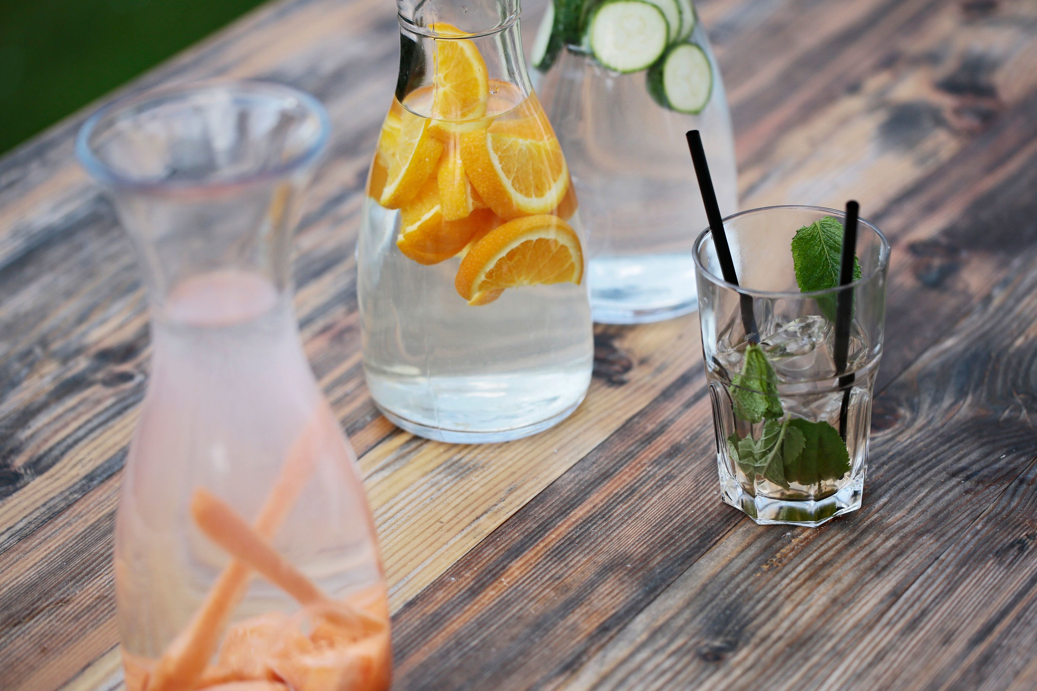 Three glass containers with drinks on a wooden table.