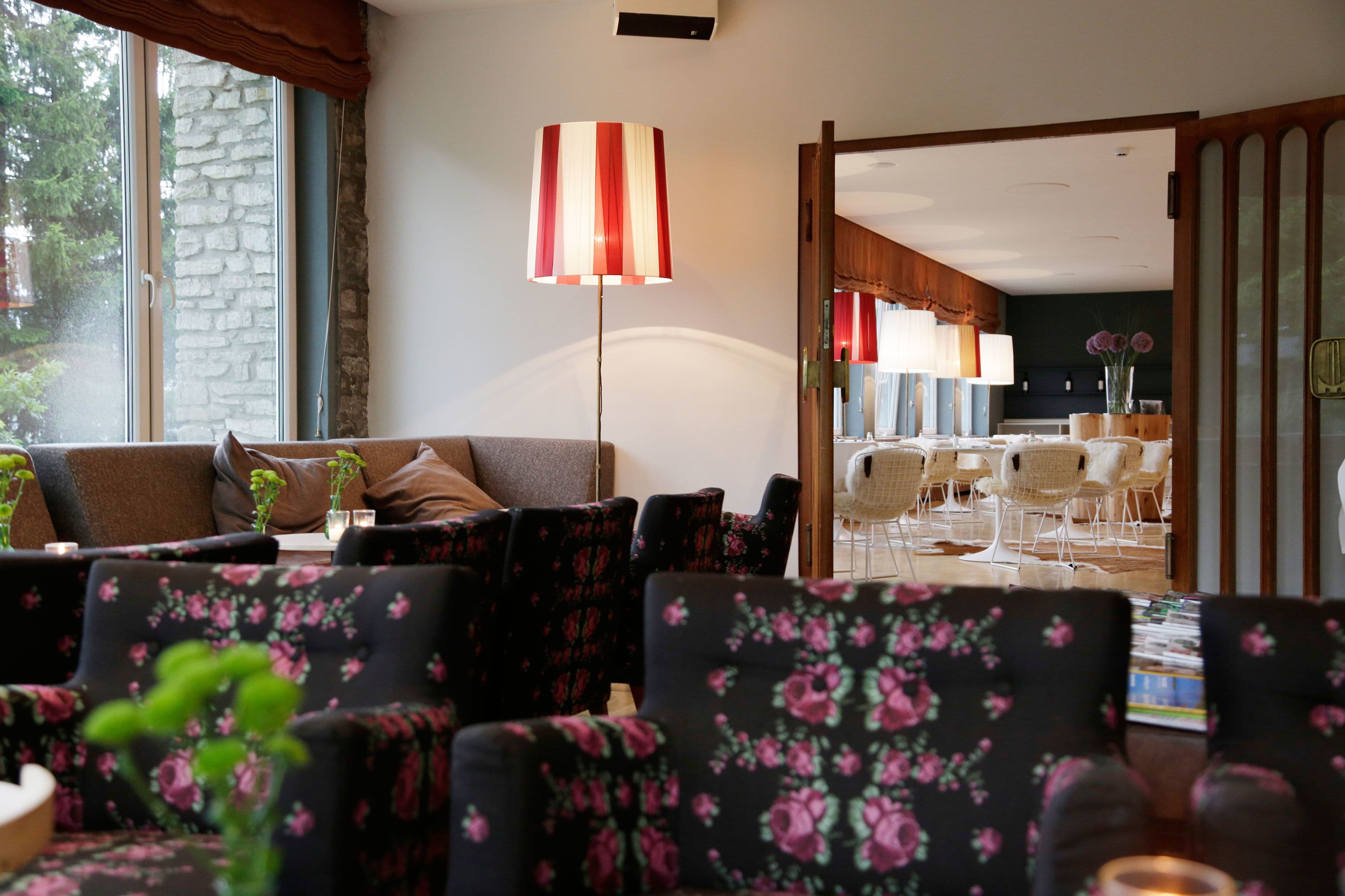 A cozy living room with a sofa, floral armchairs, and a dining area with chairs and a table.
