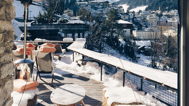 A snow-covered deck with outdoor seating and a view of a mountainous town. - Miramonte (Bad Gastein)