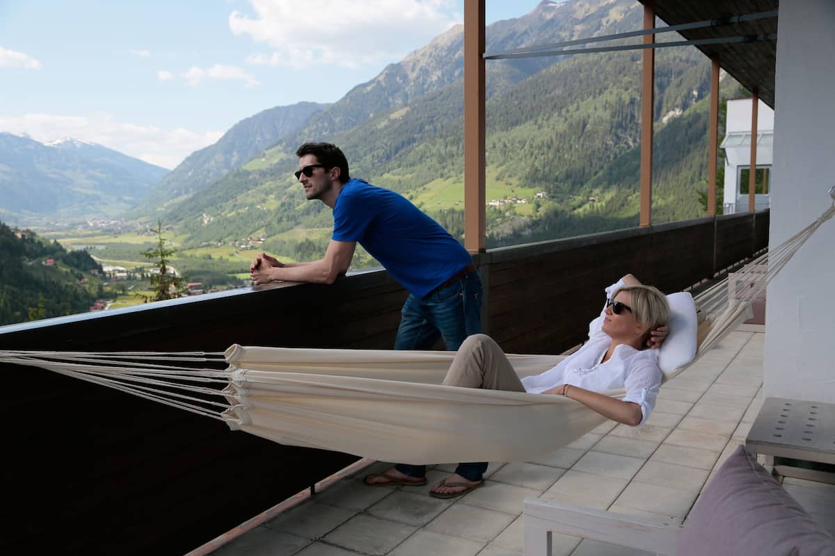 A hammock on a balcony overlooking a mountainous landscape.