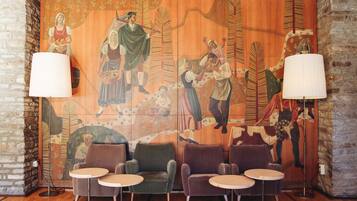 A room with a mural, four armchairs, and two small tables.