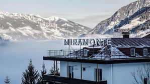 A building with a sign reading "MIRAMONTES" in a mountainous area with snow-covered peaks and a lake in the background. - Miramonte (Bad Gastein)