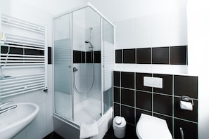 A modern bathroom with a glass-enclosed shower, a white sink, and a toilet.