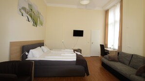 Een hotelkamer met een bed, een slaapbank, een televisie en een bureau.