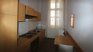 Een kleine keuken met houten kastjes, een spoelbak en een eettafel met een stoel.