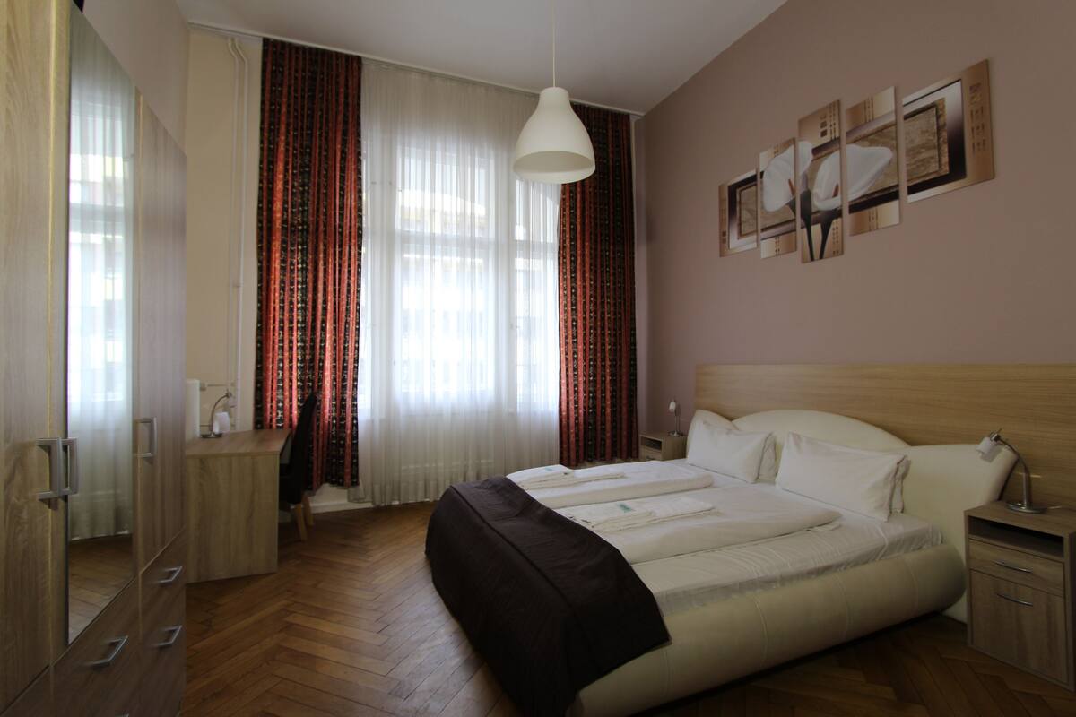 A bedroom with a large bed, a desk, and a wardrobe.