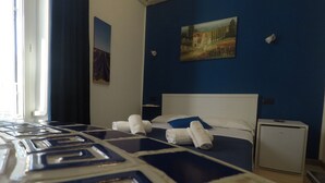 Une chambre d’hôtel avec un lit, une petite table de chevet, une commode et un tableau au mur.
