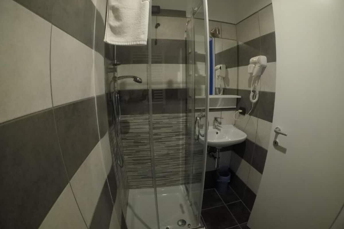 A bathroom with a glass-enclosed shower, a sink, and a towel hanging on the wall.