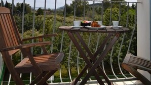 A balcony with a table and two chairs, overlooking a scenic landscape with trees and hills. - Hotel Dell'Ancora (Villasimius)