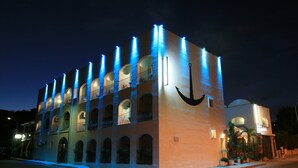 A building with multiple balconies and a large anchor symbol on the facade. - Hotel Dell'Ancora (Villasimius)