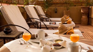 A breakfast setup with a table, chairs, and a variety of food and drink items. - Riad Aderbaz (Marrakech)