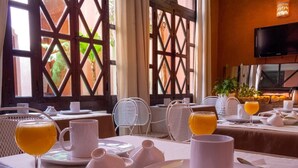 A breakfast setup with a table set for two, including plates, glasses, and a pitcher. - Riad Aderbaz (Marrakech)