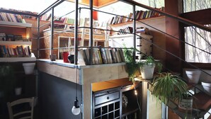 A cozy reading nook with bookshelves, a chair, and a small table with a potted plant. - Villa Alba Boutique Hotel (Pescara)