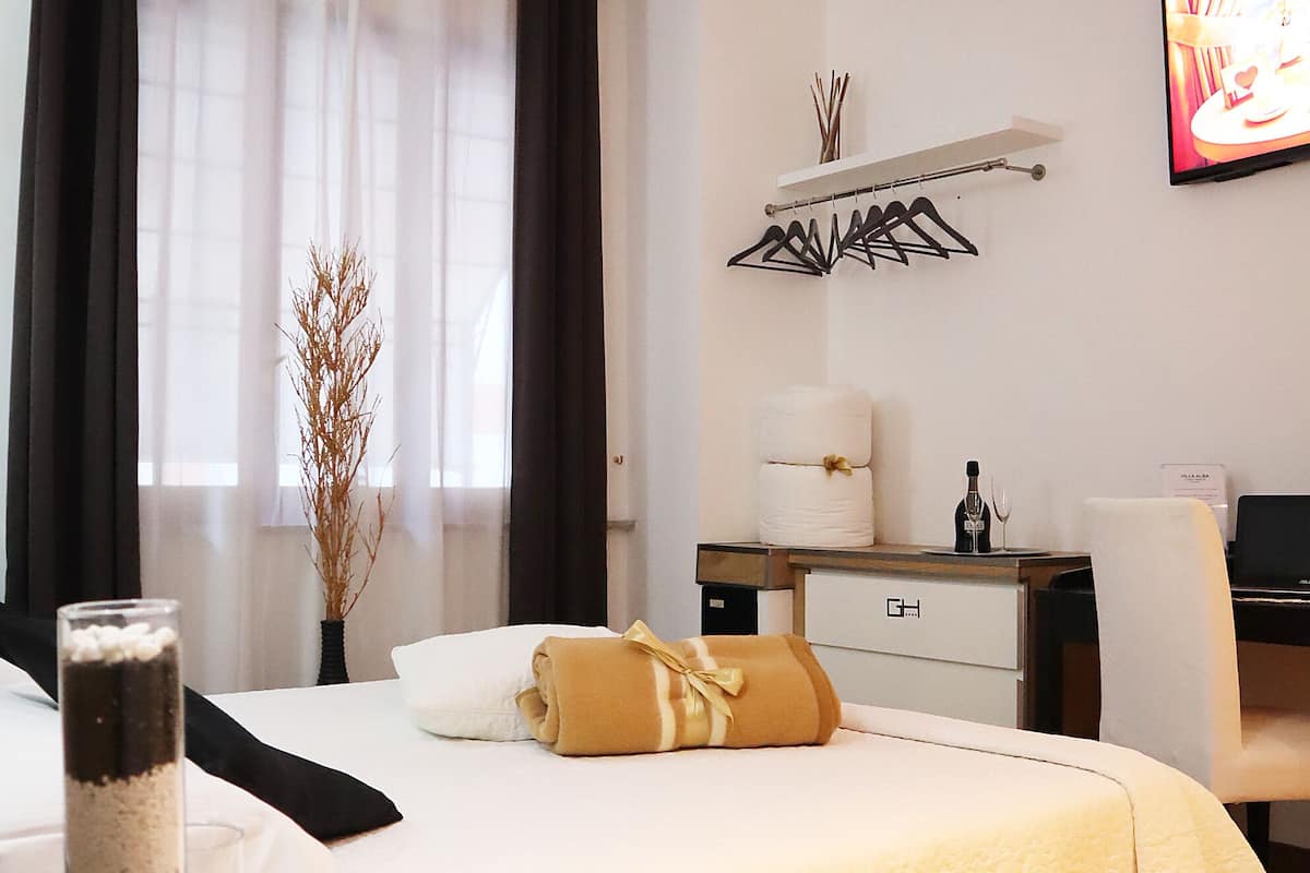 A hotel room with a bed, bedside table, and a TV on the wall.