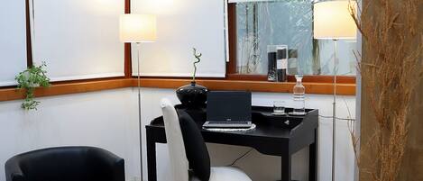 A modern office space with a desk, two chairs, a lamp, and a potted plant.