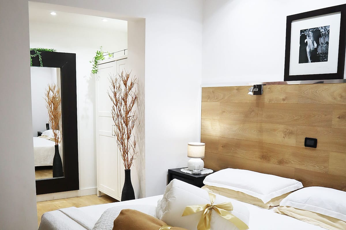A modern hotel room with a large bed, a bedside table with a lamp, and a framed picture on the wall.