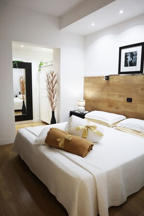 Habitación de hotel moderna con una cama grande, una mesita de noche con lámpara y un cuadro en la pared.