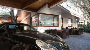 A black convertible car parked in a covered outdoor area with wicker furniture and a stone floor. - Villa Alba Boutique Hotel (Pescara)