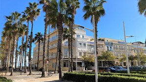 A street lined with palm trees and a building with multiple floors and balconies. - Hotel Miramar Valencia (Valencia)