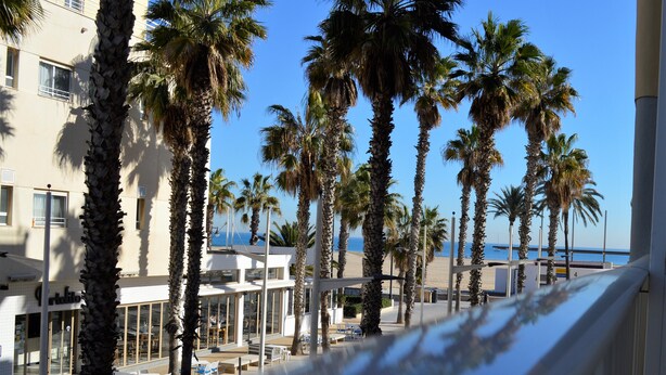 A beachfront hotel with palm trees, outdoor seating, and a view of the sea. - Hotel Miramar Valencia (Valencia)
