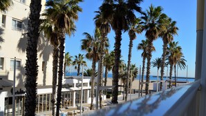 Un hôtel situé en bord de mer, agrémenté de palmiers, doté d’une terrasse et offrant une vue sur l’océan.