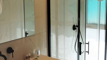 A modern bathroom with a glass-enclosed shower, a large mirror, and a beige vanity.