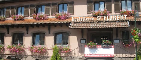 A building with a sign reading "Hostel St. Florent" and a staircase leading to the entrance.
