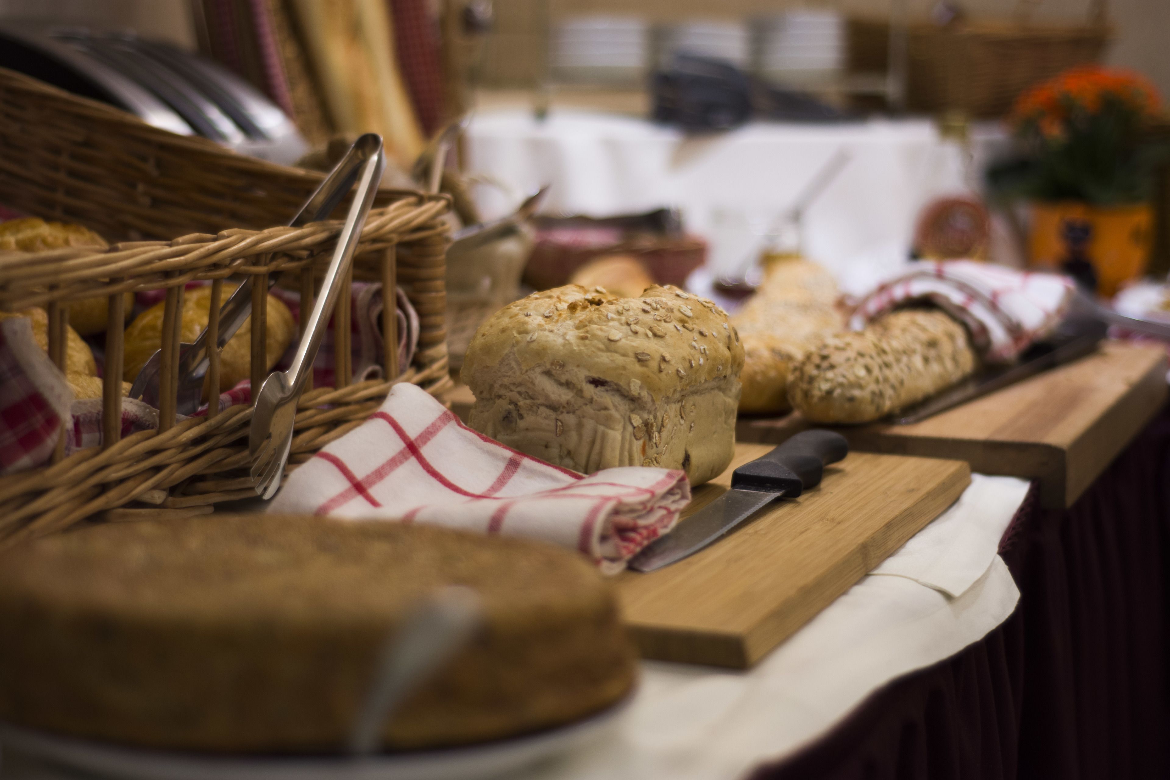 A variety of breads and pastries on a table, with a knife and a basket nearby.