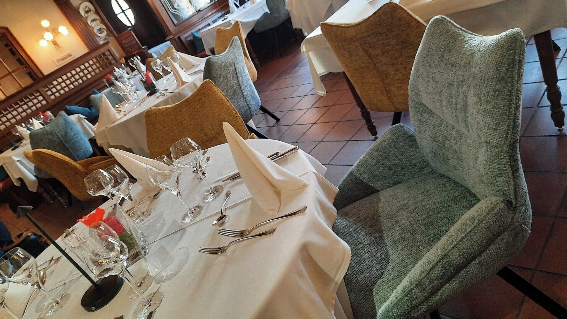 Un restaurante con mesas dispuestas para comer, sillas y suelo de baldosas.