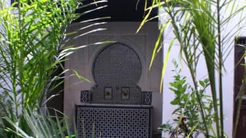 A courtyard with a central archway, surrounded by lush green plants.