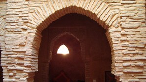 An arched doorway with a rough stone texture, leading into a dimly lit interior. - Riad Felloussia (Meknes)