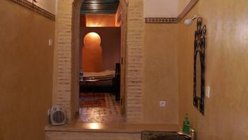 A narrow hallway with a tiled floor, a small sink, and a mirror on the wall.