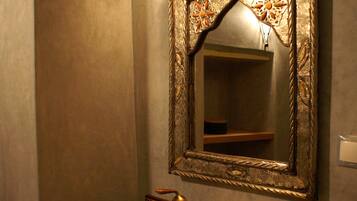 A bathroom with a decorative mirror, a sink, and a towel rack.