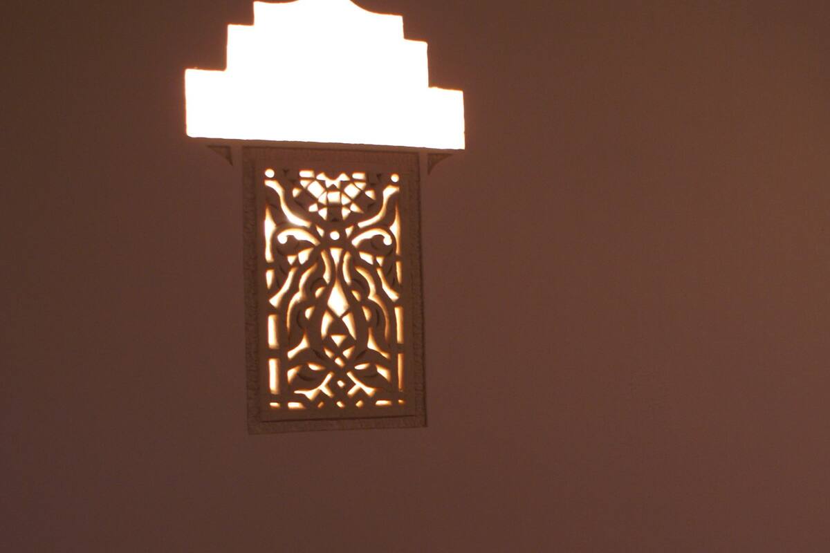 Un luminaire mural au design géométrique, avec un support à bougie placé en dessous.