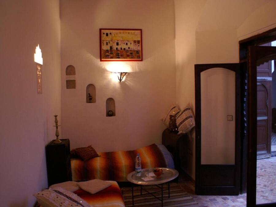 Uma sala de estar acolhedora com um sofá, uma mesinha com um copo e uma porta que dá para um pátio.