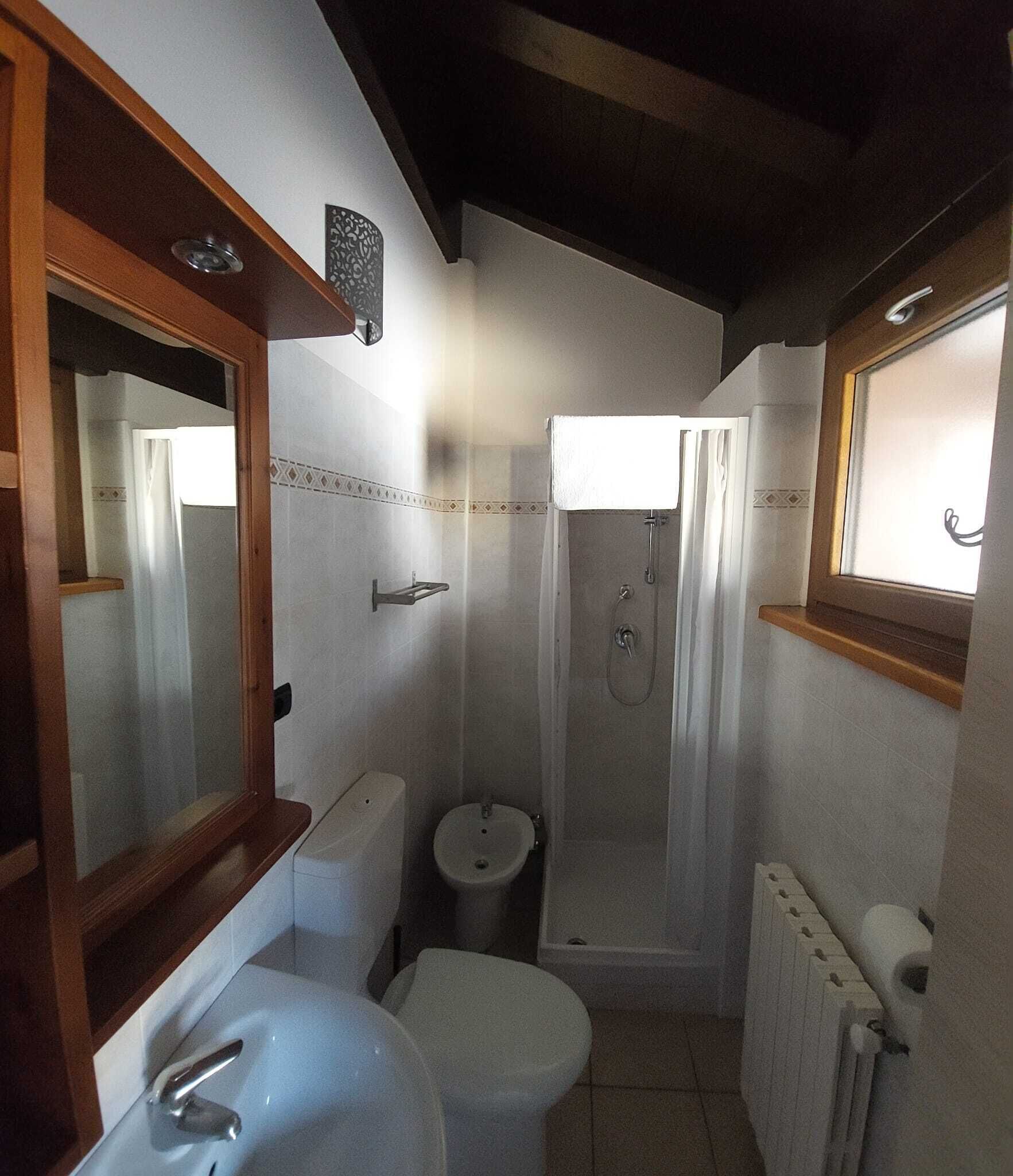 Un baño pequeño y funcional con inodoro, lavamanos y ducha.