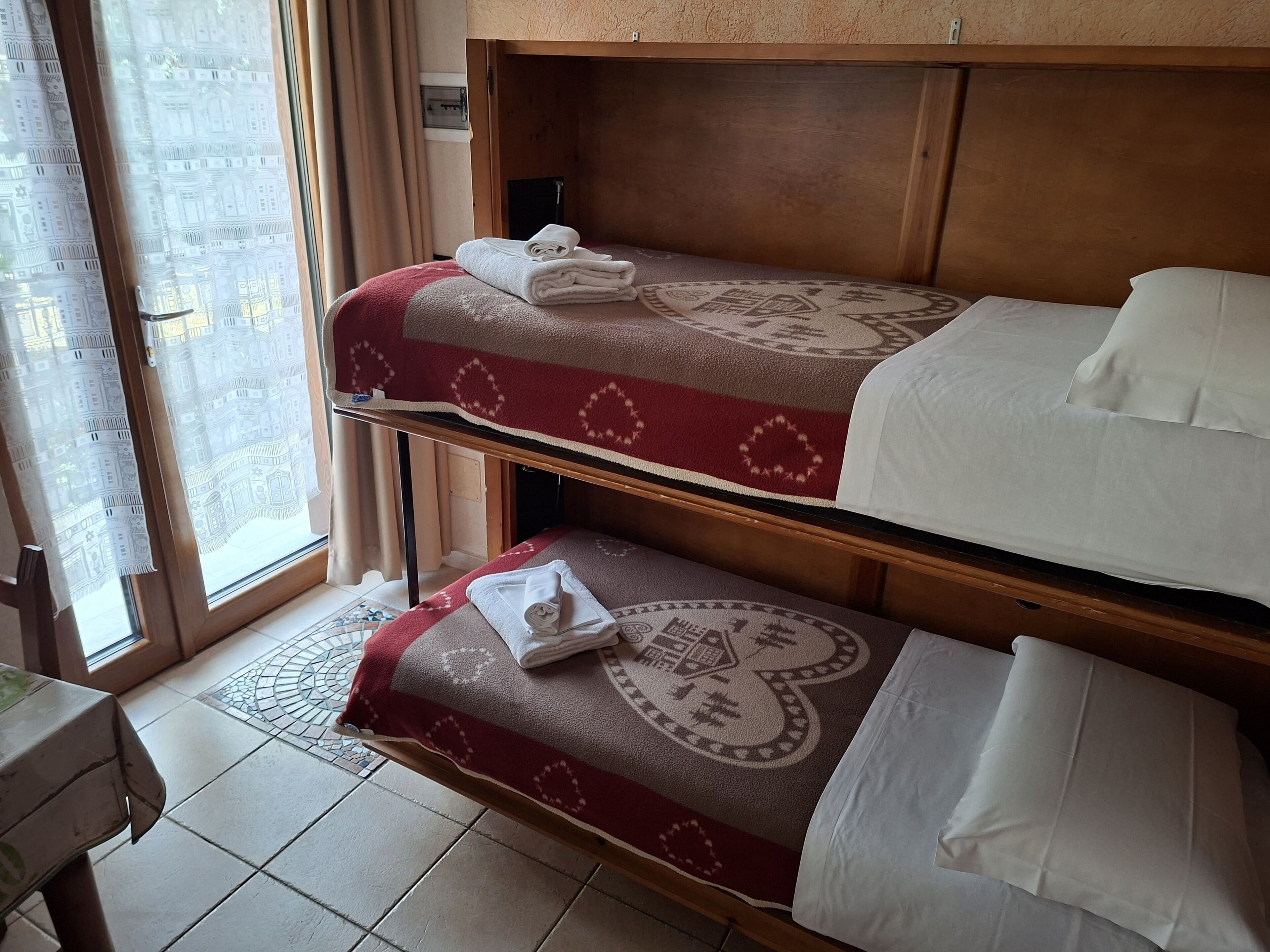 Habitación de hotel con dos camas, cada una con una colcha de cuadros rojos y blancos y almohadas blancas.
