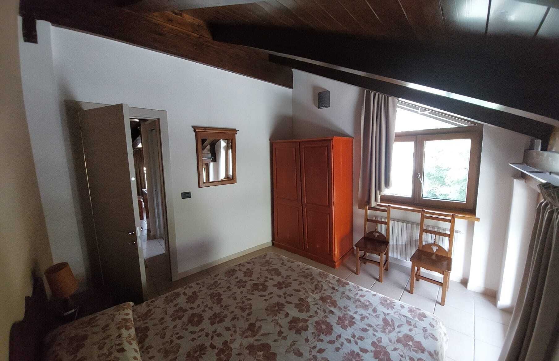 A bedroom with a bed, wardrobe, and a window with curtains.
