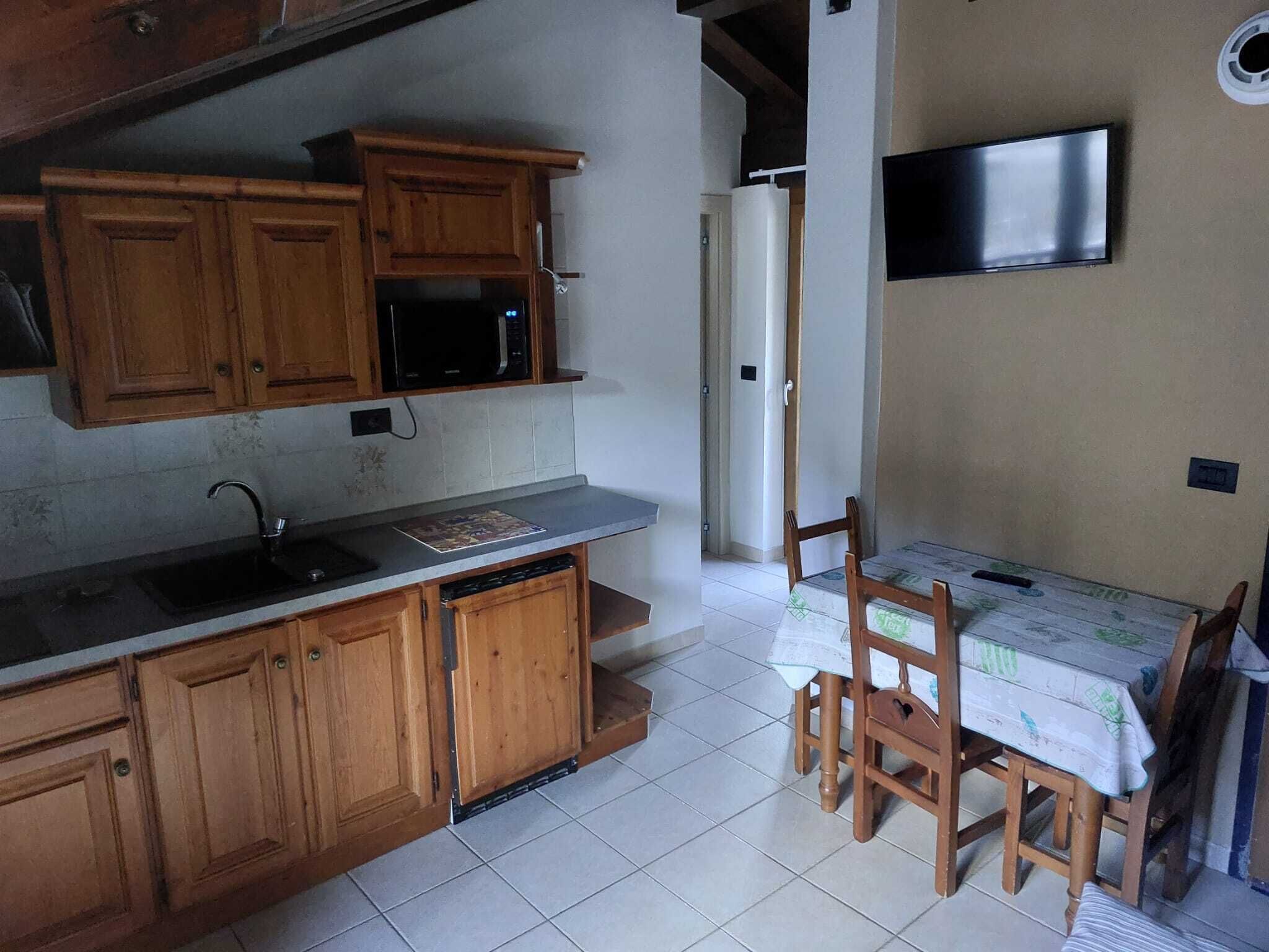 A kitchen with wooden cabinets, a microwave, a sink, and a dining table with chairs.