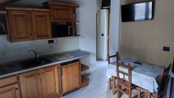 A kitchen with wooden cabinets, a microwave, a sink, and a dining table with chairs.