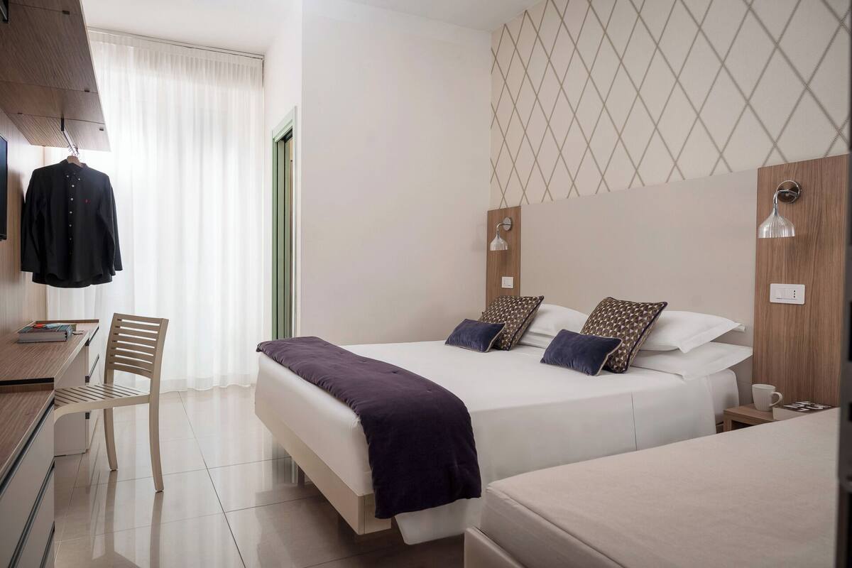 A hotel room with a bed, a desk, and a chair.