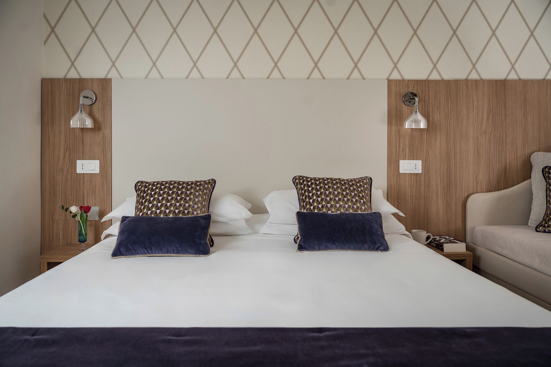 A hotel room with a large bed, two bedside tables, a nightstand, a lamp, and a chair.