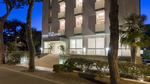 A hotel with a modern facade, multiple balconies, and a well-lit entrance. - Hotel Calypso (Rimini)