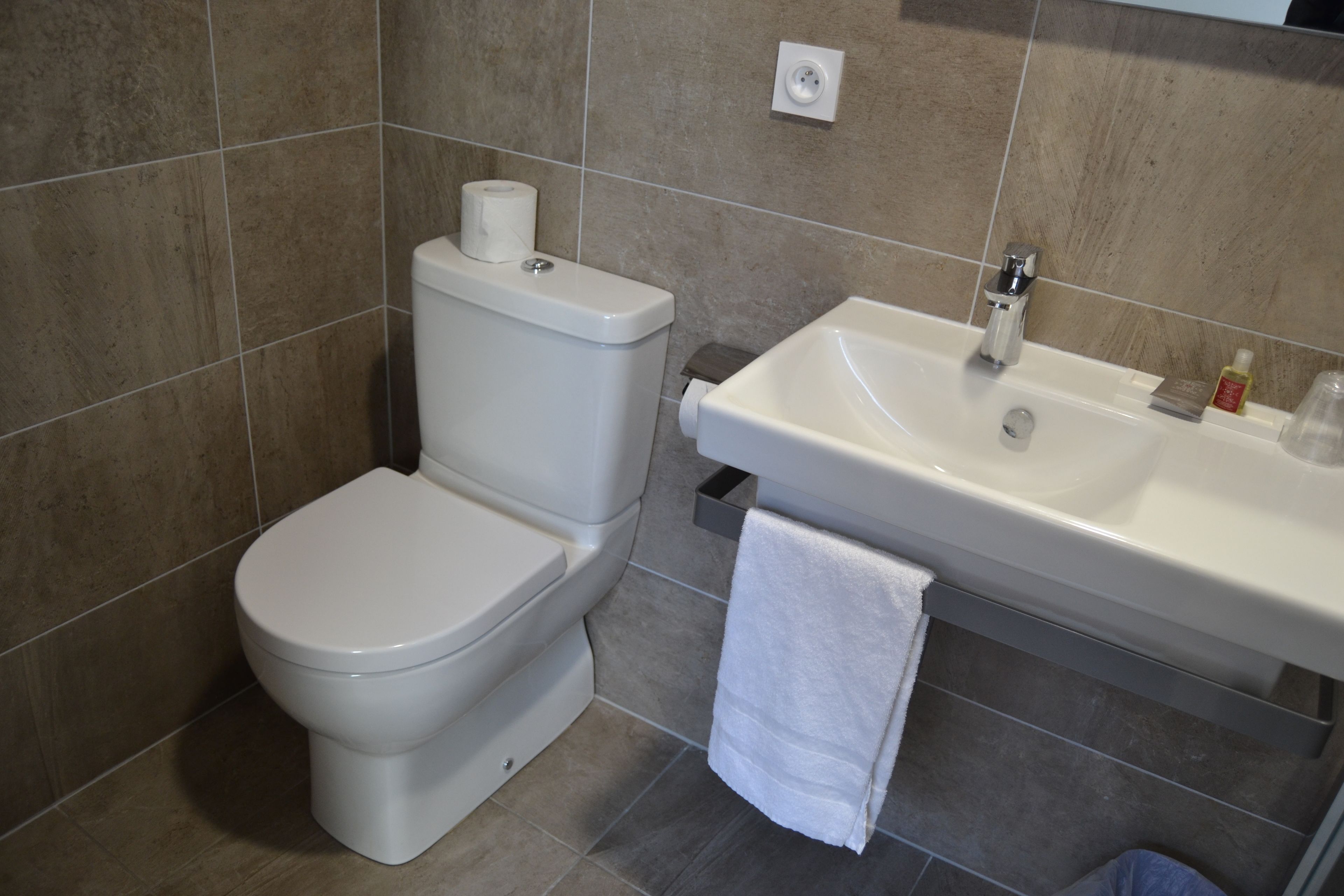 A bathroom with a toilet, sink, and a towel hanging on the wall.
