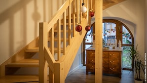A wooden staircase with a view of a room featuring a wooden dresser and a plant. - Hotel Restaurant Saint Nicolas (Riquewihr)