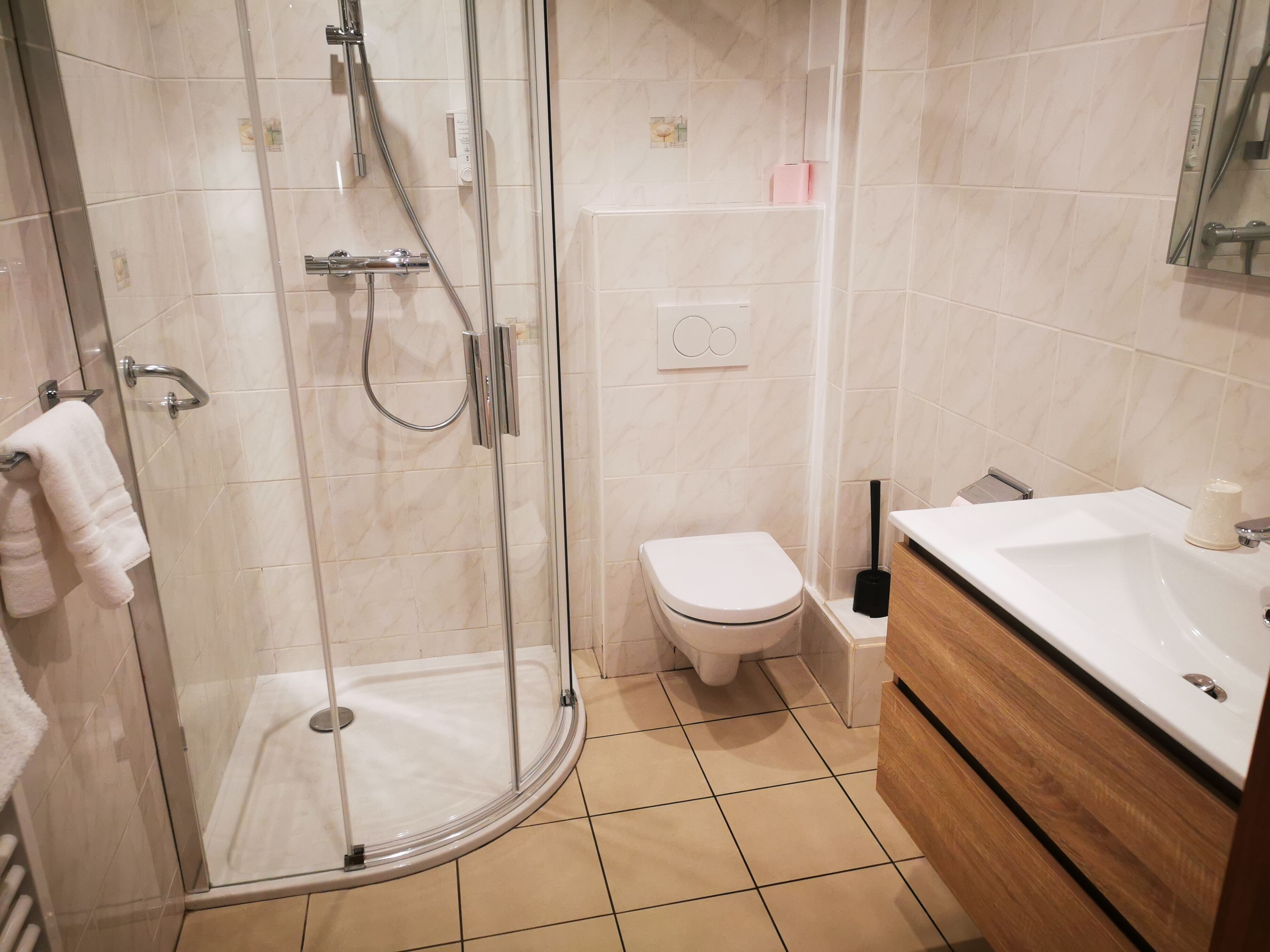 Een moderne badkamer met een douchecabine van glas, een toilet en een wastafelmeubel met een wastafel.
