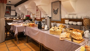 A breakfast buffet with a variety of food items and beverages, a coffee station, and a decorative wall with a chicken illustration. - Hotel Restaurant Saint Nicolas (Riquewihr)