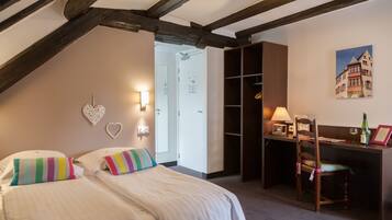 A bedroom with a bed, a desk, and a chair. There is a door leading to another room.