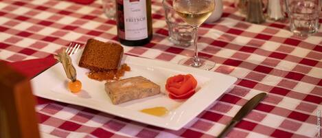 Una mesa de comedor con mantel a cuadros, una botella de vino, una copa de vino y un plato de comida.